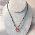 Detail of red mushroom pendant on yellow, blue, and grey braided rope necklace - Red