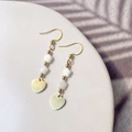 Detail of gold dangling earrings with white flower beads and engraved heart charms - Heart Shell Style