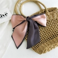 Nastro in raso bicolore rosa e marrone annodato a fiocco su una borsa di paglia - Rosa e Viola