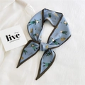 Light blue narrow silk scarf with cartoon girl print and Moore lettering on white shirt - Girl Bag Print Blue