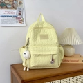 Yellow textured pleated backpack with white plush doll charm on wooden cabinet - Small With Pendant / Yellow