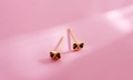 Detailed close-up of golden panda stud earrings with black enamel on pink background - Panda Style (k59)