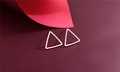 Macro shot of polished silver geometric triangle stud earrings on a dark red background - Isosceles Triangle (F18)