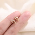 Pendientes dorados de imperdible con pequeñas perlas blancas y cristales en la mano - Estilo de Clip Dorado (C14)