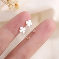 Pendientes minimalistas de trébol de cuatro hojas plateados sostenidos sobre fondo de lino - Estilo de Trébol de Cuatro Hojas Plateado (B221)