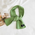Grass green ribbed knit scarf with woven brand label on soft white minimalist backdrop - Verdant