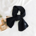 Black ribbed knit scarf with woven label on soft textured background, warm winter accessory - Black