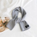 Solid grey knitted double-sided scarf with stylish label in minimalist home setting - Gray