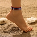 Détail de bracelets de cheville en perles colorées portés sur une plage de sable fin - Rayures Classiques Rouge Blanc Bleu Noir (26347-8pcs)