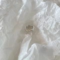 Detalle de anillo plateado irregular ondulado con acabado de espejo sobre papel blanco - Plateado