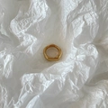 Anillo dorado minimalista con textura de lava líquida sobre fondo blanco liso - Dorado