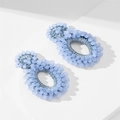 Handmade light blue seed bead earrings with oval rings and woven texture on white background - Blue