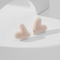 Detailed macro view of soft pink flocked heart stud earrings on a geometric stand - Beige