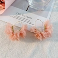 Detailopname van handgemaakte roze organza bloemenoorbellen op een witte nepbont ondergrond - Roze