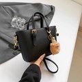 Minimalist black bucket bag in litchi grain leather with gold hardware and plush charm - Black With Pendant