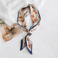 Elegante lange smalle sjaal met oranje bloemmotief op een beige stoffen achtergrond - Slaapmutsje Kakie