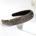 Close-up of wide padded headband with dark grey rhinestones on a white display stand - Black