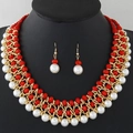 Dettaglio di un set gioielli boho intrecciato con perle rosse, bianche e metallo dorato - Rosso