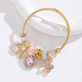 Detail of gold twisted wire bracelet with pink crystal hearts and Love charms - Pink