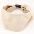 Close-up of beige elastic yoga headband with knit texture and handmade fabric label - Off White