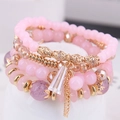 Bohemian multilayer beaded bracelet with pink crystals and gold tassel on white stand - Pink