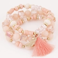Handmade layered bracelet set in pink and gold with wing charm and tassel accent - Pink