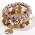 Detail of multi-layer beaded bracelet set featuring a gold Tree of Life charm pendant - Coffee