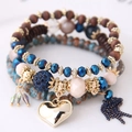 Makro-Detail des mehrlagigen Perlenarmbands mit goldenem Herzanhänger und Quasten - Blau