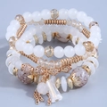 Detail view of multi-layer beaded bracelet set with gold tassels and crystal charms - White