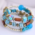 Bracciale boho multistrato con perline blu, elementi in legno e ciondoli in vetro floreale - Blu