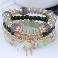 Macro detail of Bohemian multilayered green beaded bracelet with rose gold charms - Light Green
