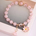 Detailansicht eines rosa Gänseblümchen-Anhängers und Kristallperlen am Damenarmband - Rosa