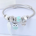 Detailed view of silver wire bracelet with blue owl, feather and crystal charms - Green
