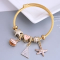 Gold stainless steel twisted cuff bracelet with heart, starfish, and shell charms - Pink