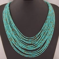 Collier bohème multicouche avec perles turquoise et accents dorés sur support - Vert