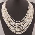 Collier bohème multicouches en perles blanches avec détails dorés sur un support noir - Blanc