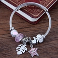 DIY charm bangle with starfish leaf and pink heart pendant on vintage wood background - Pink