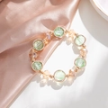 Elegante kralenarmband met groene en champagne glazen kralen op een satijnen achtergrond - Lichtgroen