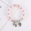 Detalle de pulsera de cristal rosa con colgantes de corazón, corona y hoja - Rosa
