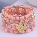 Macro detail of multi-layer beaded bracelet with engraved heart charm and crystals - Pink