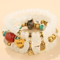 Dettaglio di perle multistrato boho con ciondoli a forma di torre Eiffel e gufo sul bracciale - Bianco