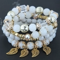 Vue détaillée de bracelets bohèmes multicouches avec feuilles dorées et perles marbrées - Blanc