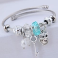 Bracciale rigido in filo d'argento con ciondolo a gufo e perle blu su supporto bianco - Blu