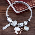 Silver twisted wire bracelet with enamel cat charm and blue gemstone on a vintage book - White