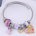 Zilveren staaldraad armband met paarse kralen en hartvormige hangers op wit plateau - Paars