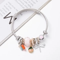 Beaded cable bracelet featuring dragonfly, pearl, and pink floral pendants on silver band - Pink