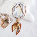 Élégant foulard en soie orange et blanc noué en boucle sur fond de fausse fourrure - Paysage Bord Orange (2)