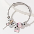 Silver charm bracelet with pink crystal beads, key pendant, and elephant dangle on stone tray - Pink