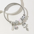Detailed shot of fox and castle charms on a silver cable texture open bangle bracelet - White