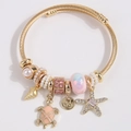 Bracelet jonc torsadé doré avec breloques de coquillages, perles, tortue et étoile de mer - Rose